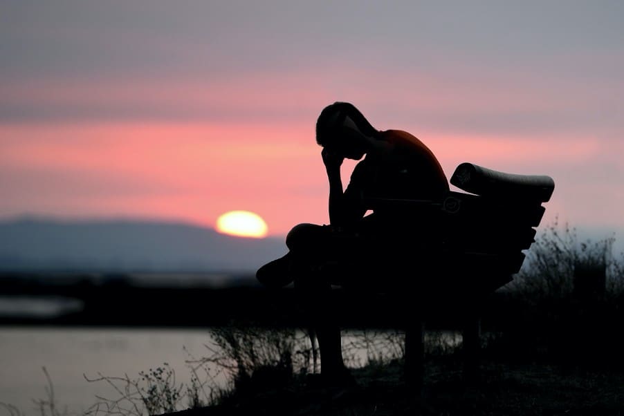 Man sits on bench with head in hand
