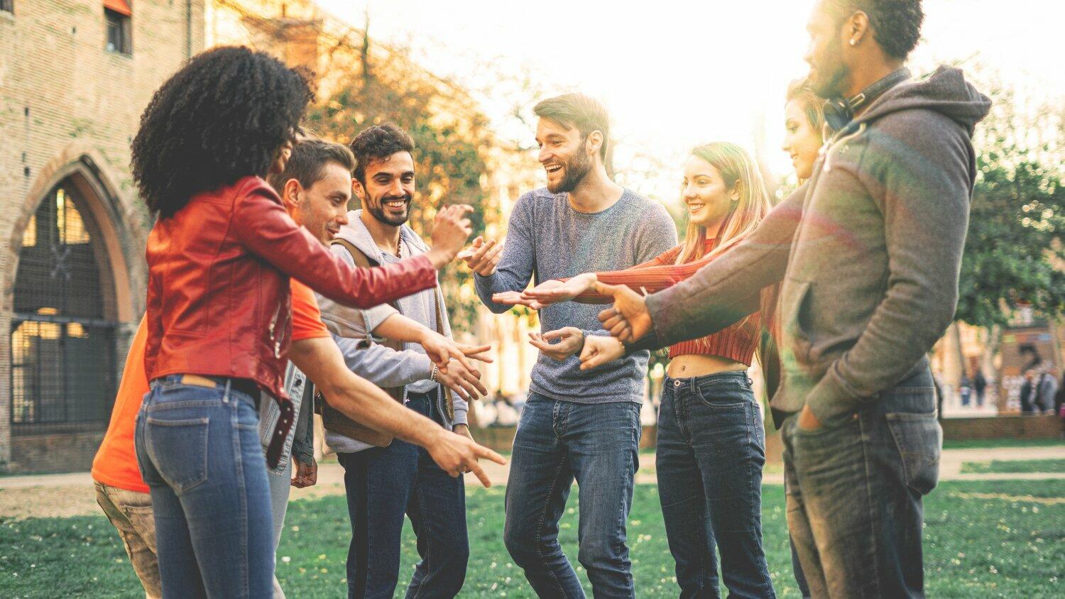 Group of multiracial people playing at Rock Paper Scissors game. Students from different culture having fun outdoors