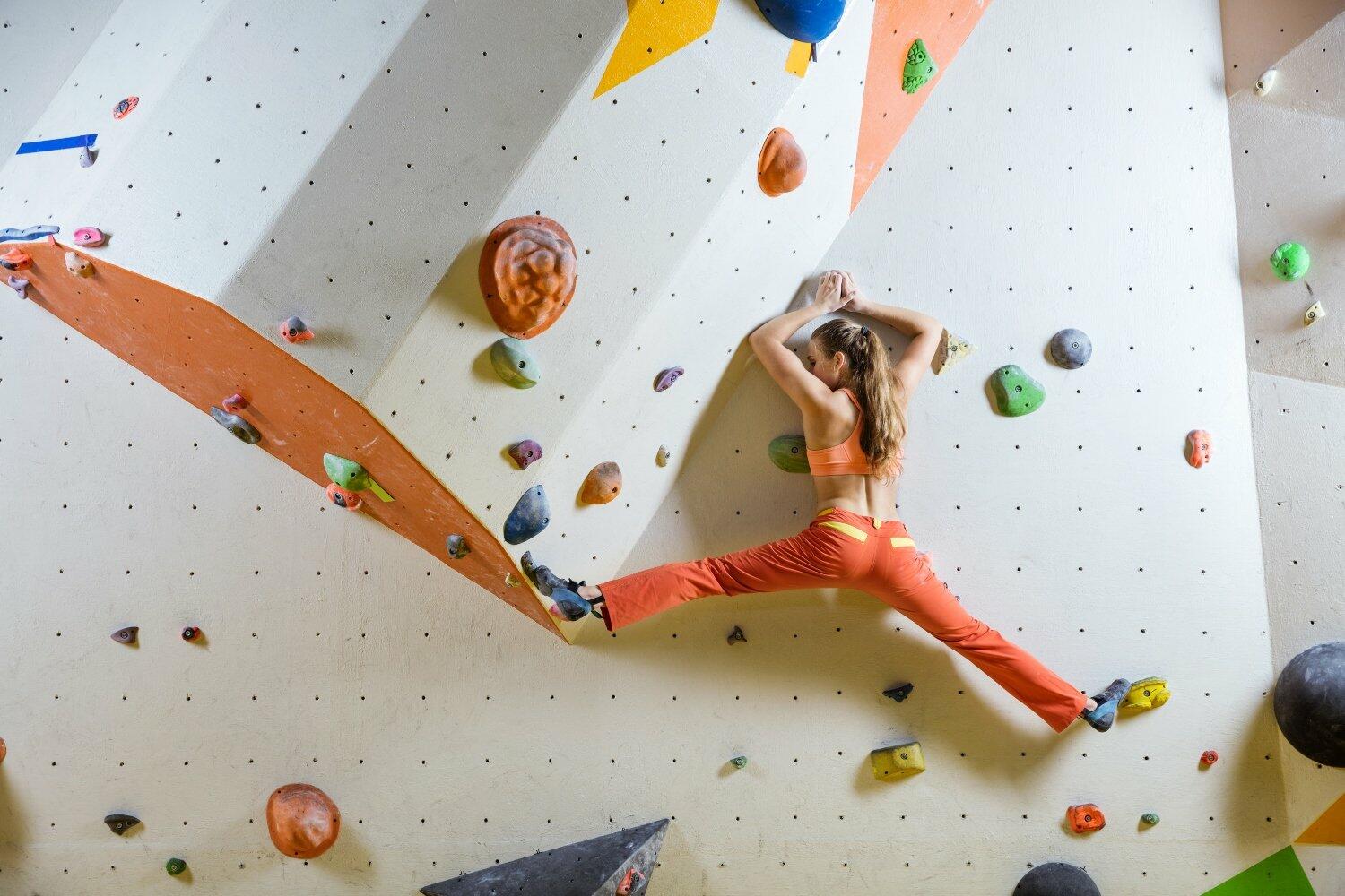 Young woman climbing challenging bouldering route. In climbing gym