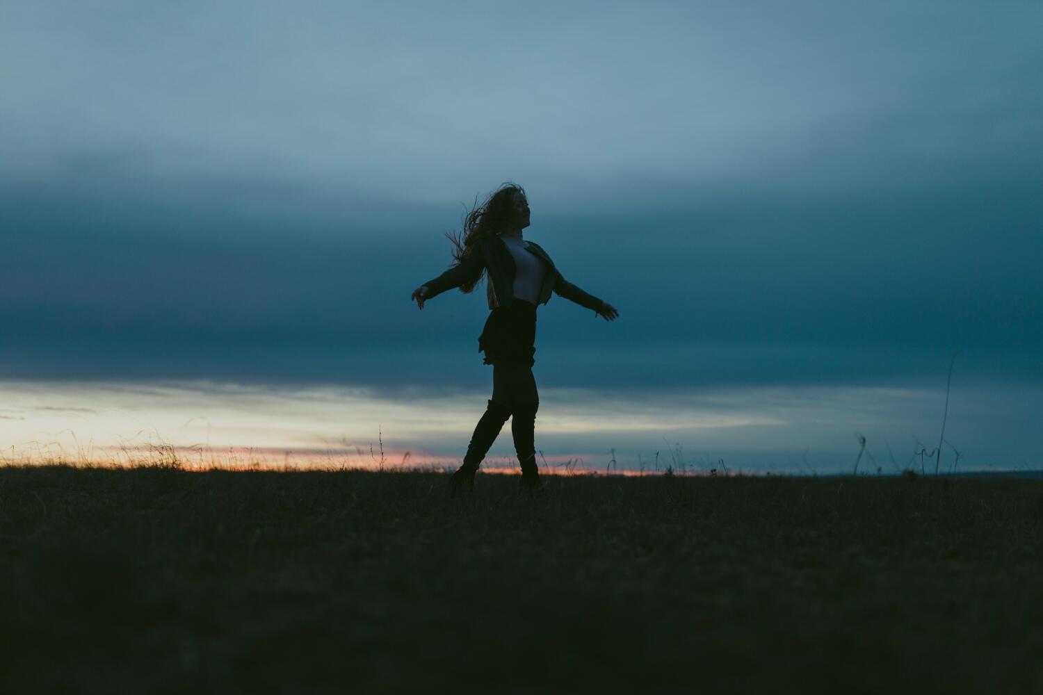 Silhouette of woman on a meadow at sunset