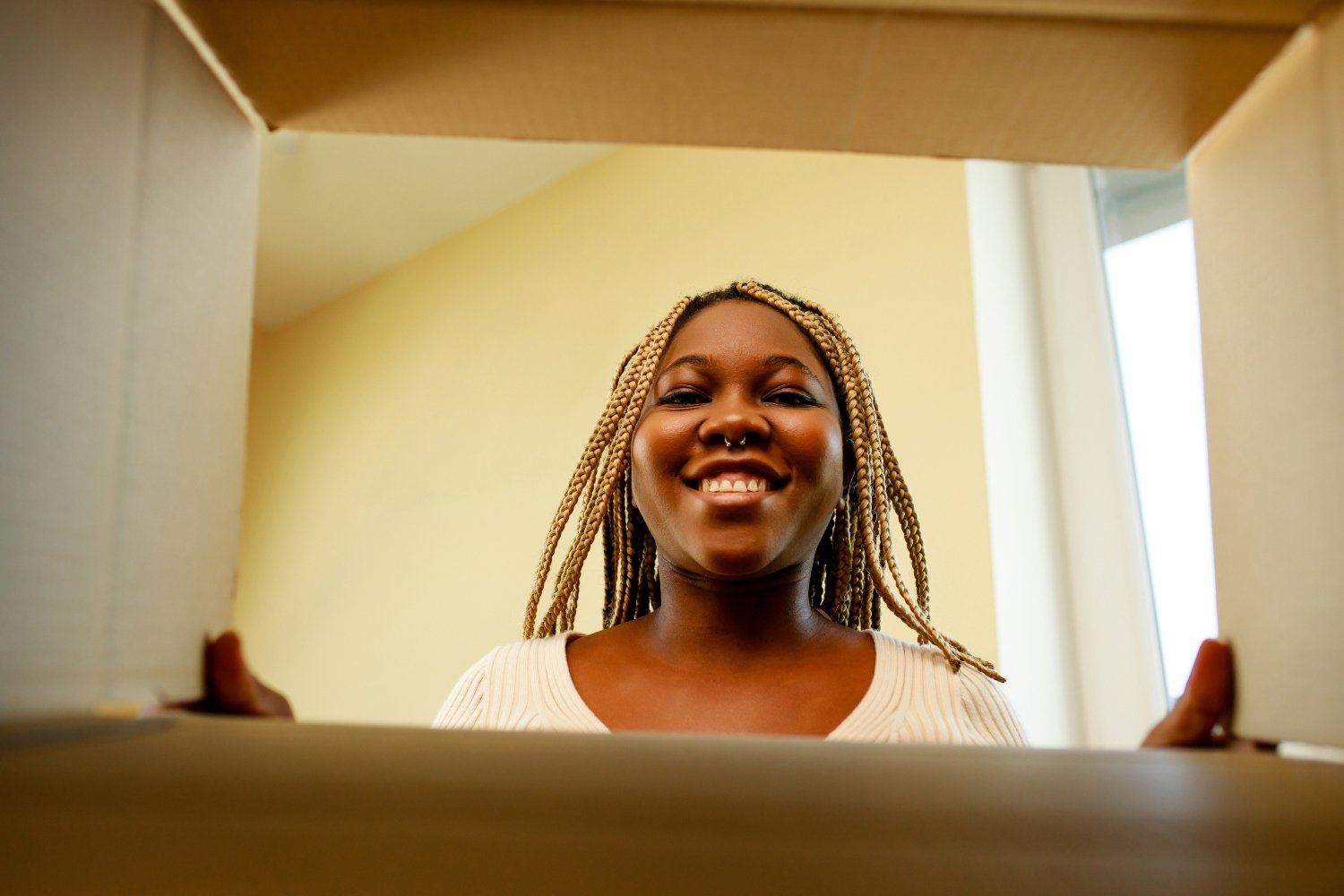 happy african american woman looking inside of box and surprised of cute pet