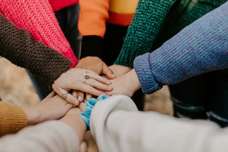 People put their hands in together in a display of support for overcoming stigma in addiction recovery.