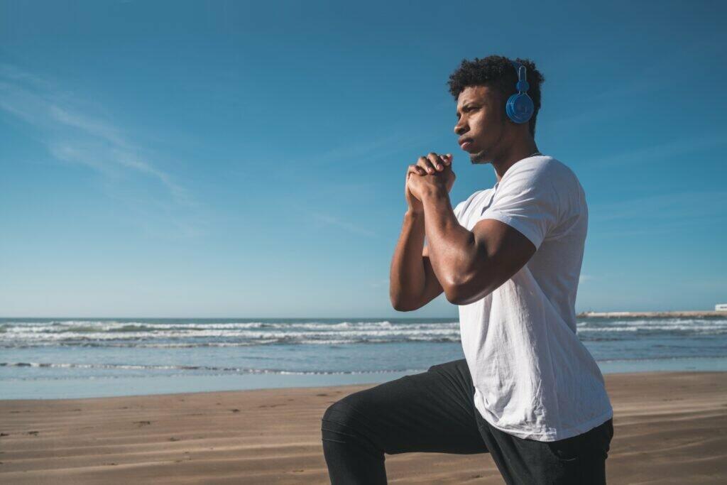Portrait of an athletic man doing exercise at the beach. Sport and healthy lifestyle concept.