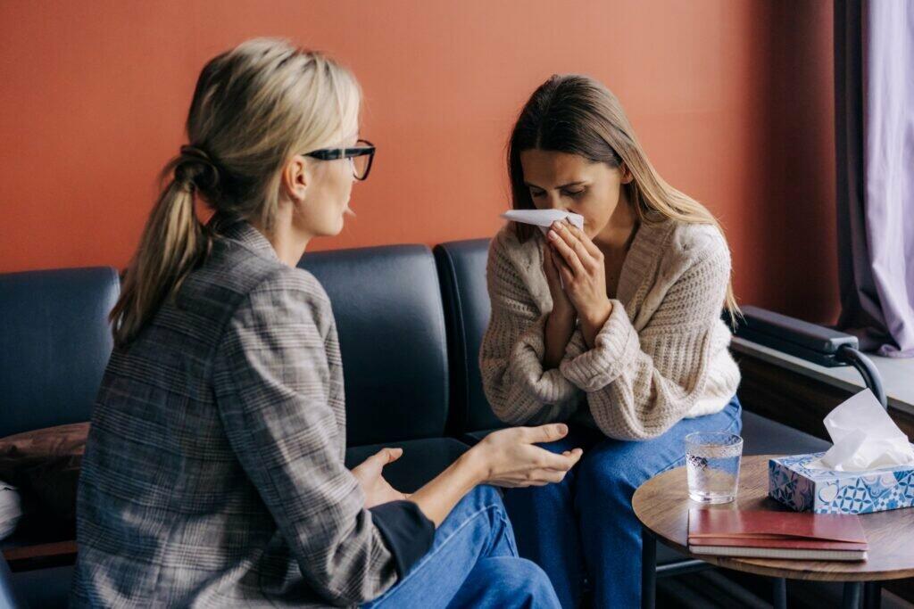 Female sitting on sofa and crying while talking to a friend