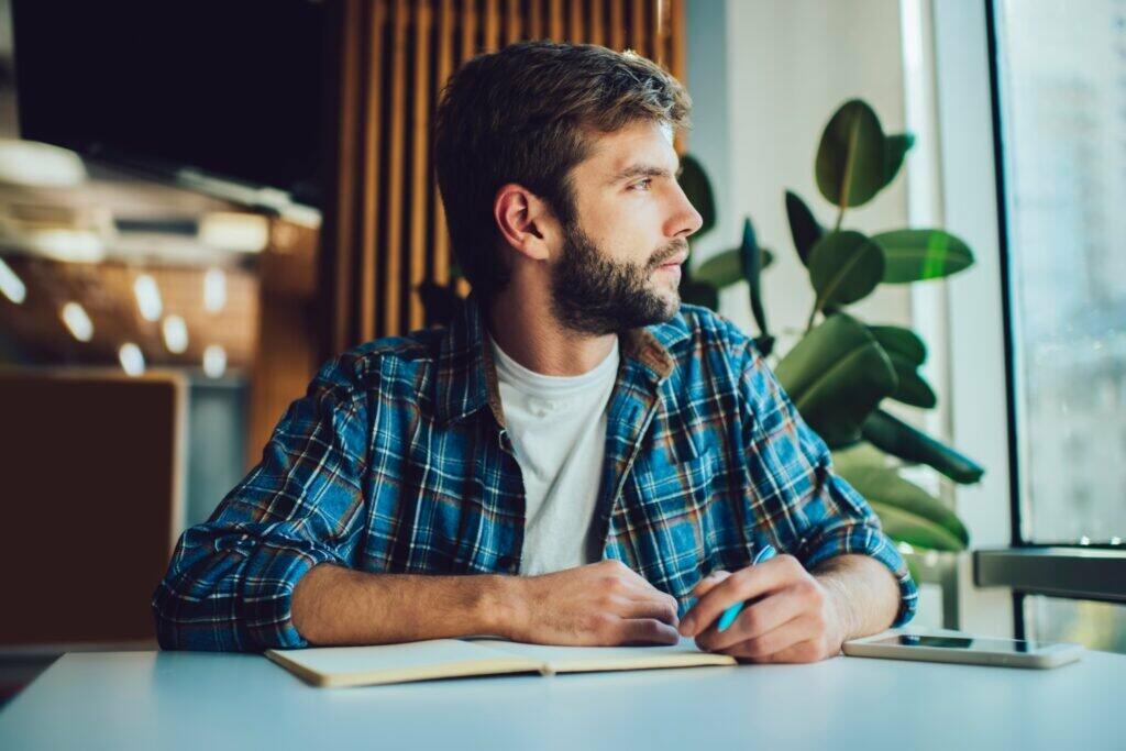 Pensive man writing in planner