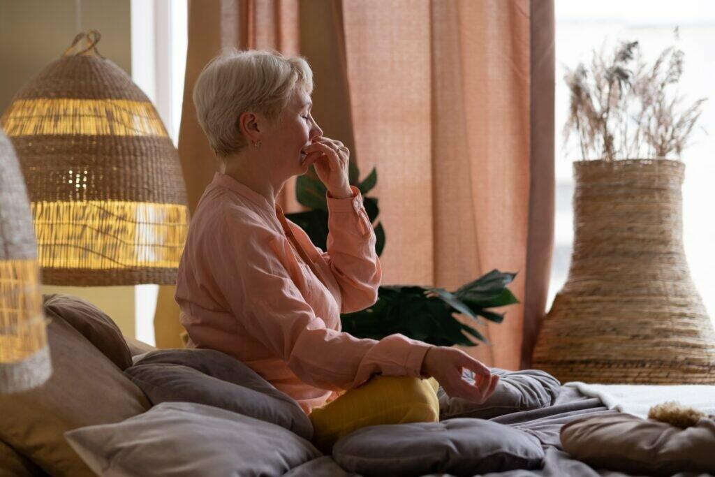 Senior woman practicing yoga at home, making Alternate Nostril Breathing exercise