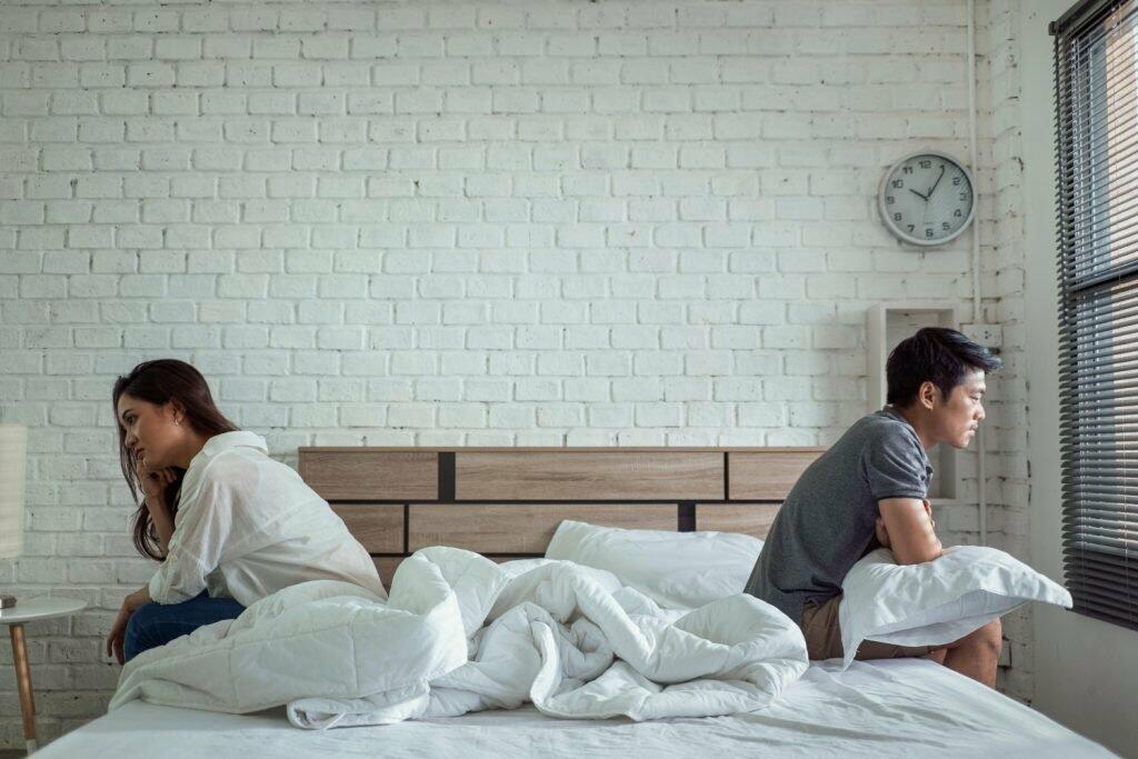 couple sitting back to back on bed